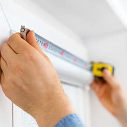 A man holding a tape measure up against a window A man holding a tape measure up against a window